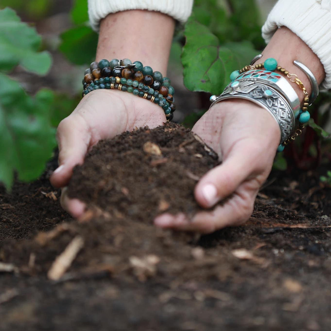 Person holding soil with greenery in the background