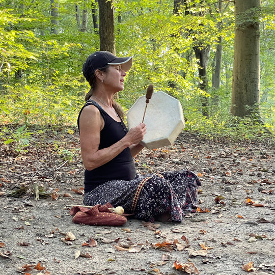 Person playing a drum in a forest setting