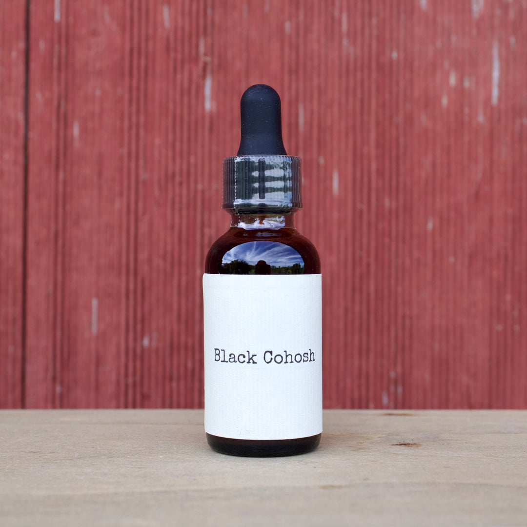 Bottle labeled 'Black Cohosh' on a wooden surface with a red wooden panel background