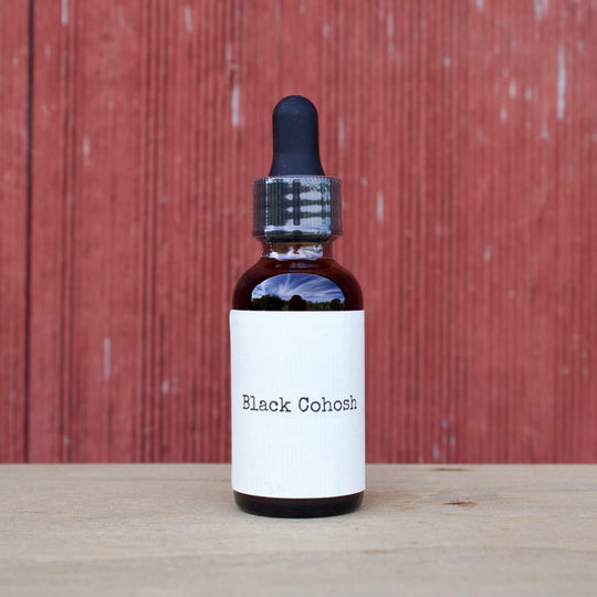Bottle labeled 'Black Cohosh' on a wooden surface with a red wooden panel background
