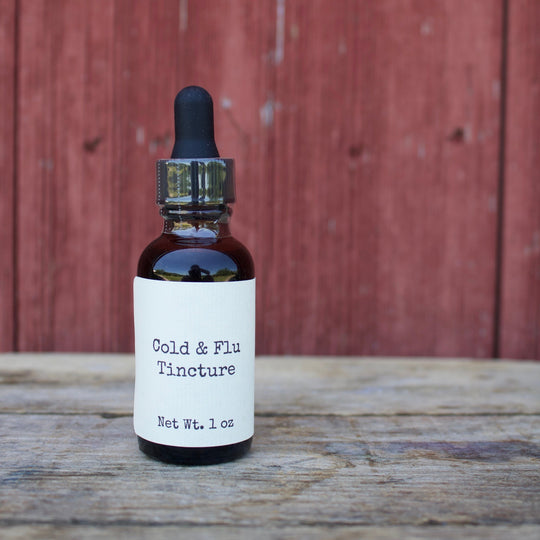 Bottle of Cold & Flu Tincture on a wooden surface with a red wooden background