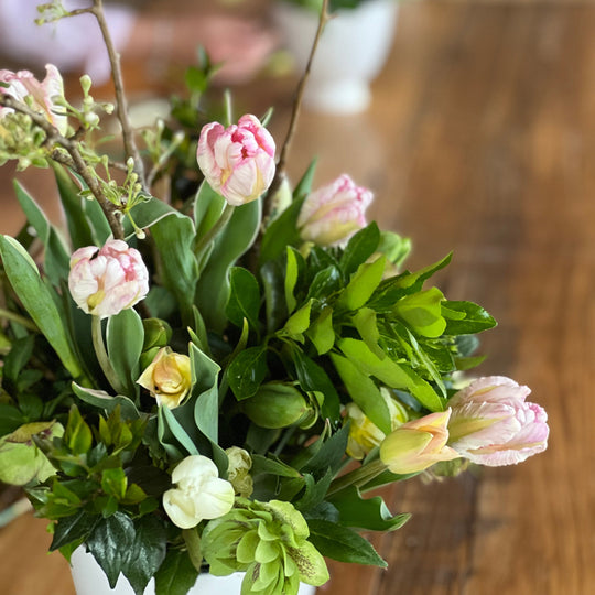 Bouquet of pink tulips and greenery on a wooden surface with a blurred background