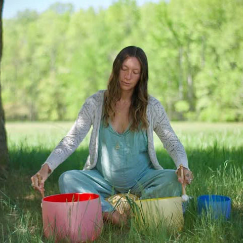 Woman sitting outdoors with colorful bowls in a natural setting