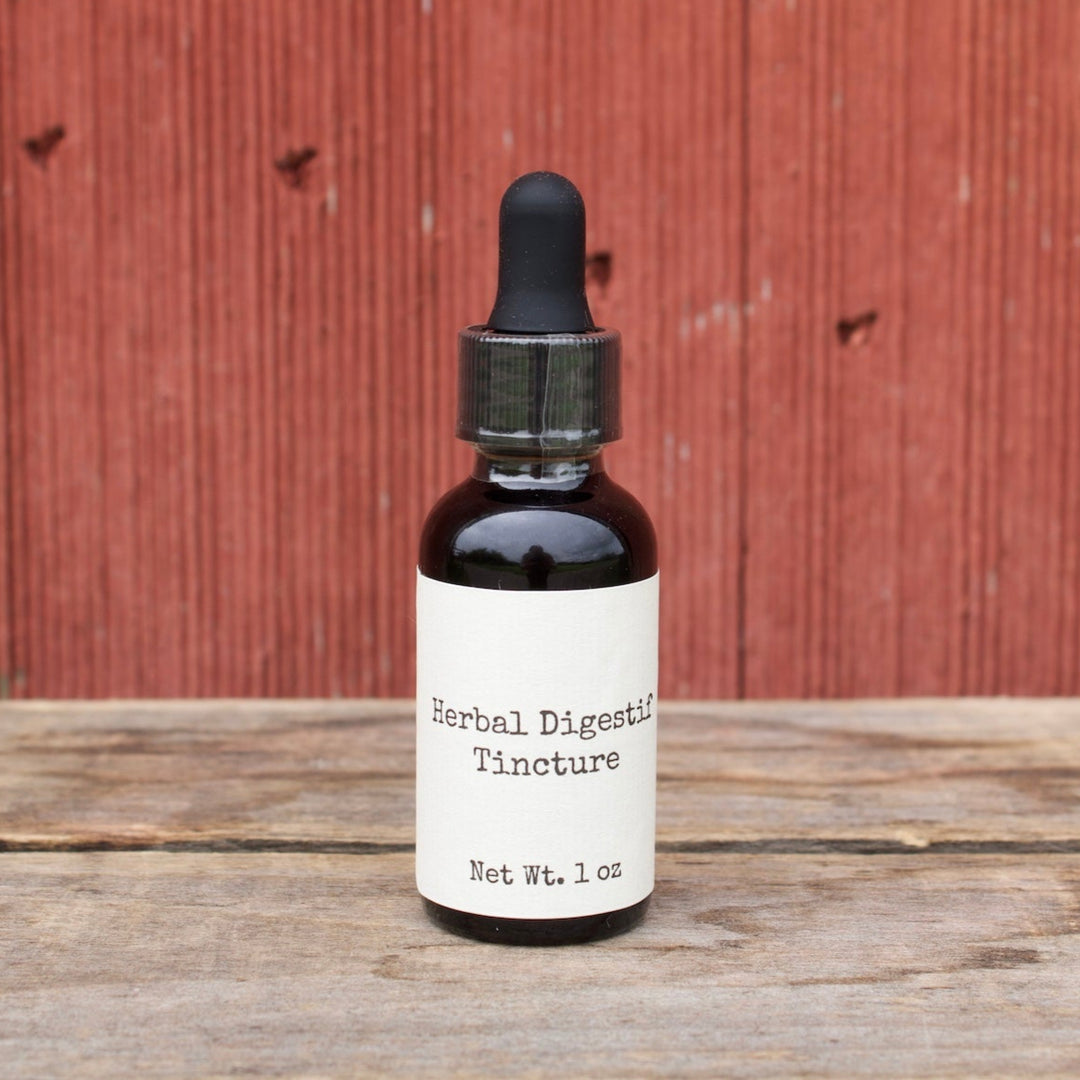 Bottle of Herbal Digestif Tincture on a wooden surface with a red wooden panel background