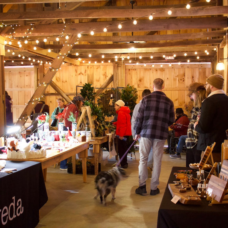Indoor event with people and booths in a rustic wooden building.