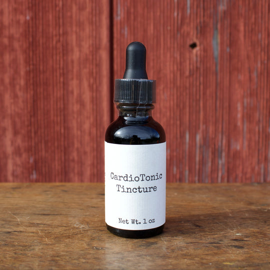 Bottle of CardioTonic Tincture on a wooden surface with a red wooden panel background