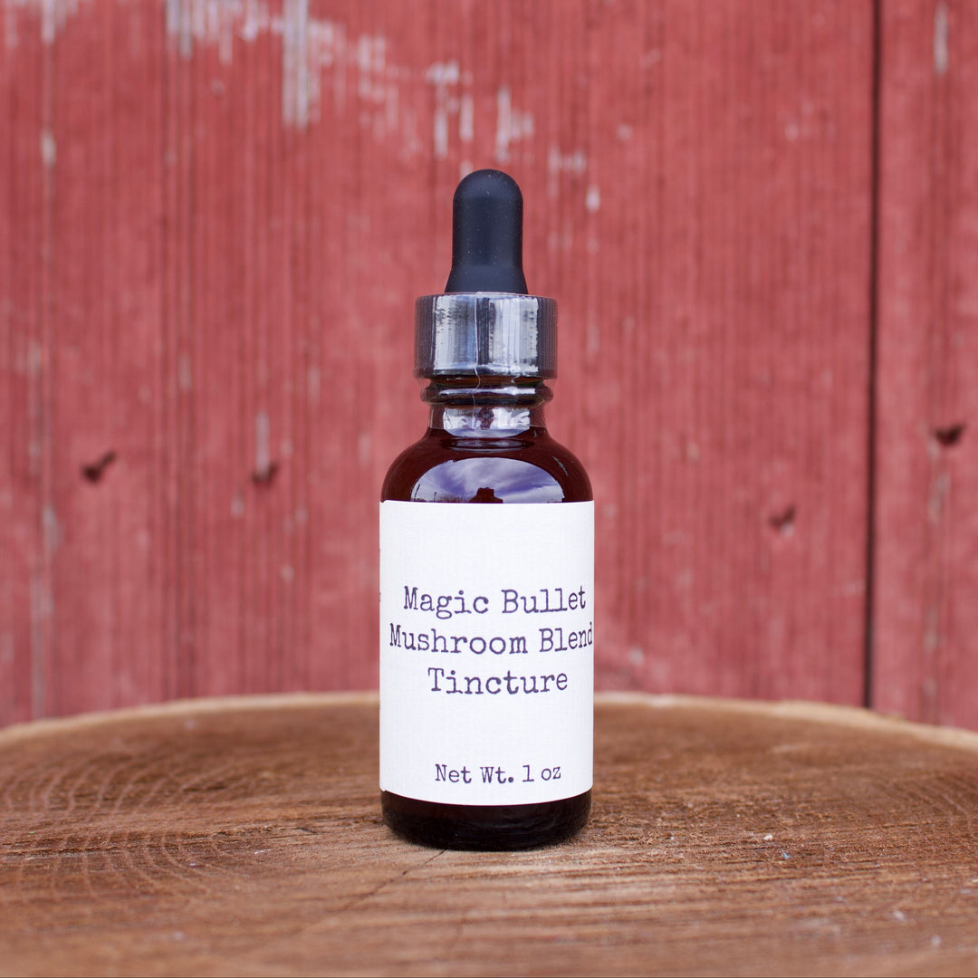 Bottle of Magic Bullet Mushroom Blend Tincture on a wooden surface with a red wooden background