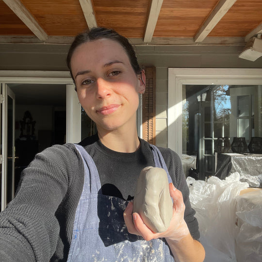 Person holding a lump of clay in front of a wooden door