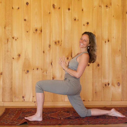 Woman practicing yoga in a room with wooden walls and a window.
