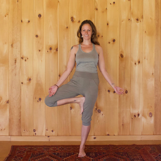 Woman practicing yoga against a wooden wall.