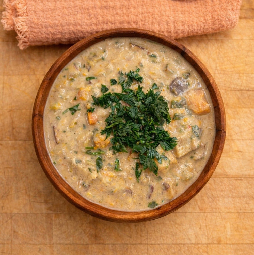 Wooden bowl of creamy soup with a cloth on a wooden surface