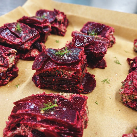 Squares of layered slices of purple food garnished with a sprig of green