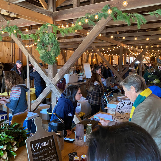 People gathered inside a wooden barn with festive decorations and food stalls.