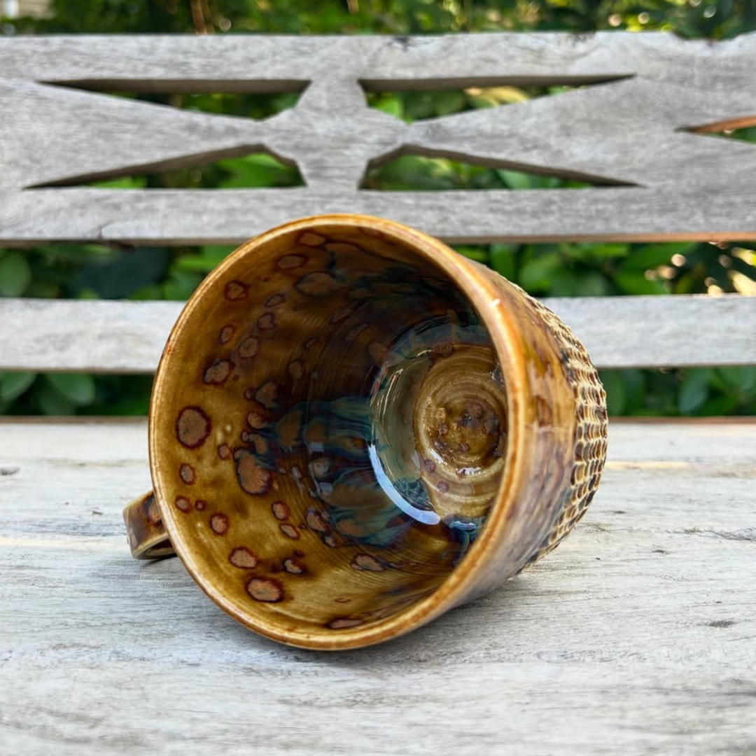 Ceramic cup with brown speckled design on a wooden bench