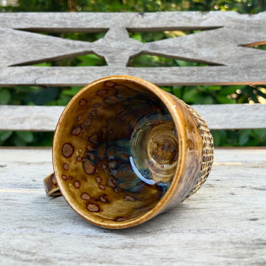 Ceramic cup with brown speckled design on a wooden bench