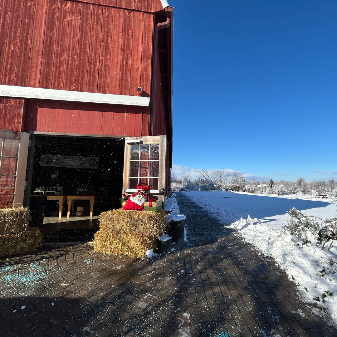 Red barn with hay bales and a Christmas decoration in a snowy landscape