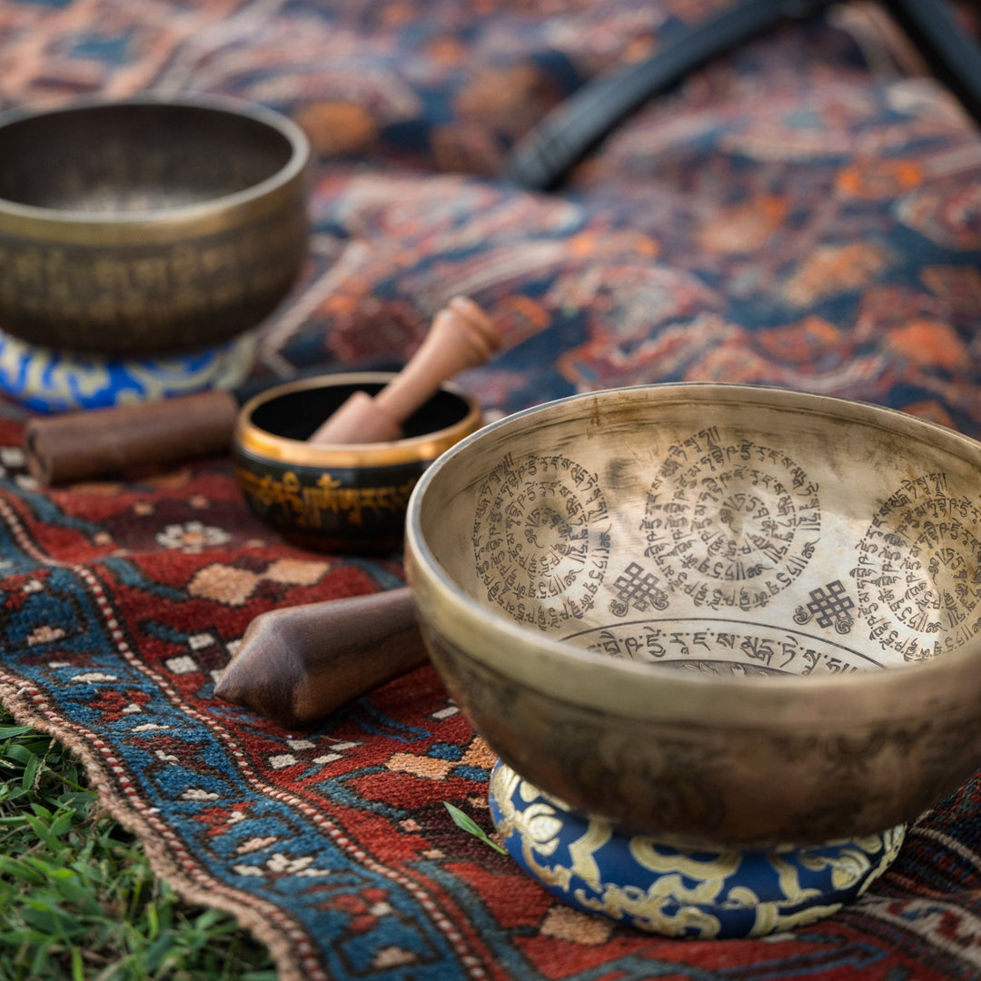 Tibetan singing bowls on a patterned rug outdoors