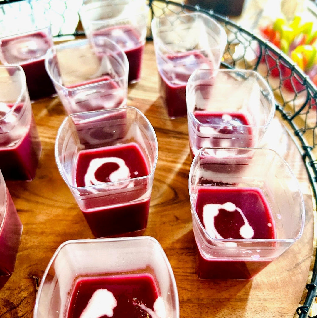 Purple sweet potato soup in clear plastic cups on a wooden surface