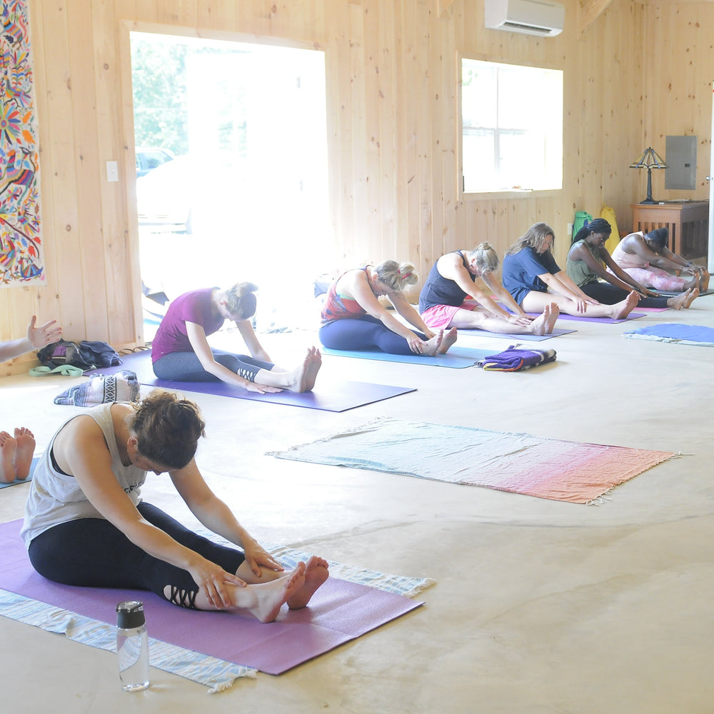 Group of people practicing yoga in a wooden studio.