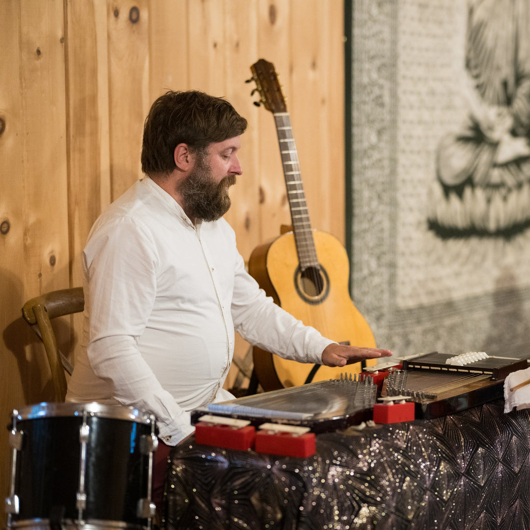 Man playing a drum set in a room with wooden walls.