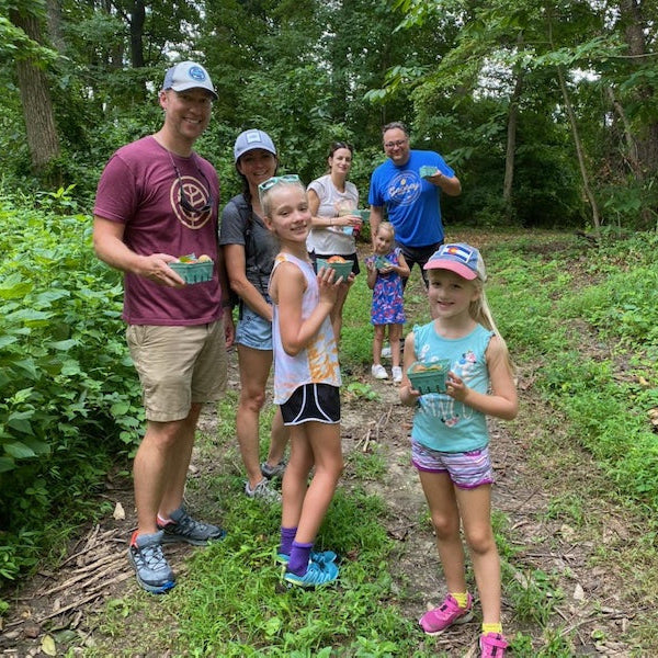 Group of people, including children, standing on a trail in a forested area.