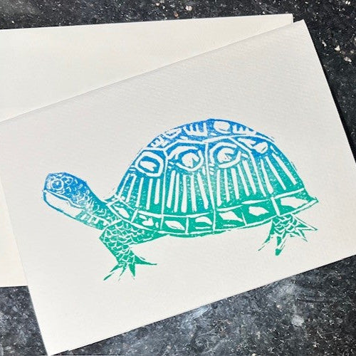 Card with a turtle design in teal on a textured surface